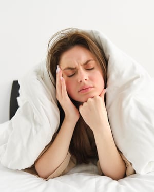 portrait-woman-rolled-blankets-bed-frowning-feeling-unwell-has-hangover-headache